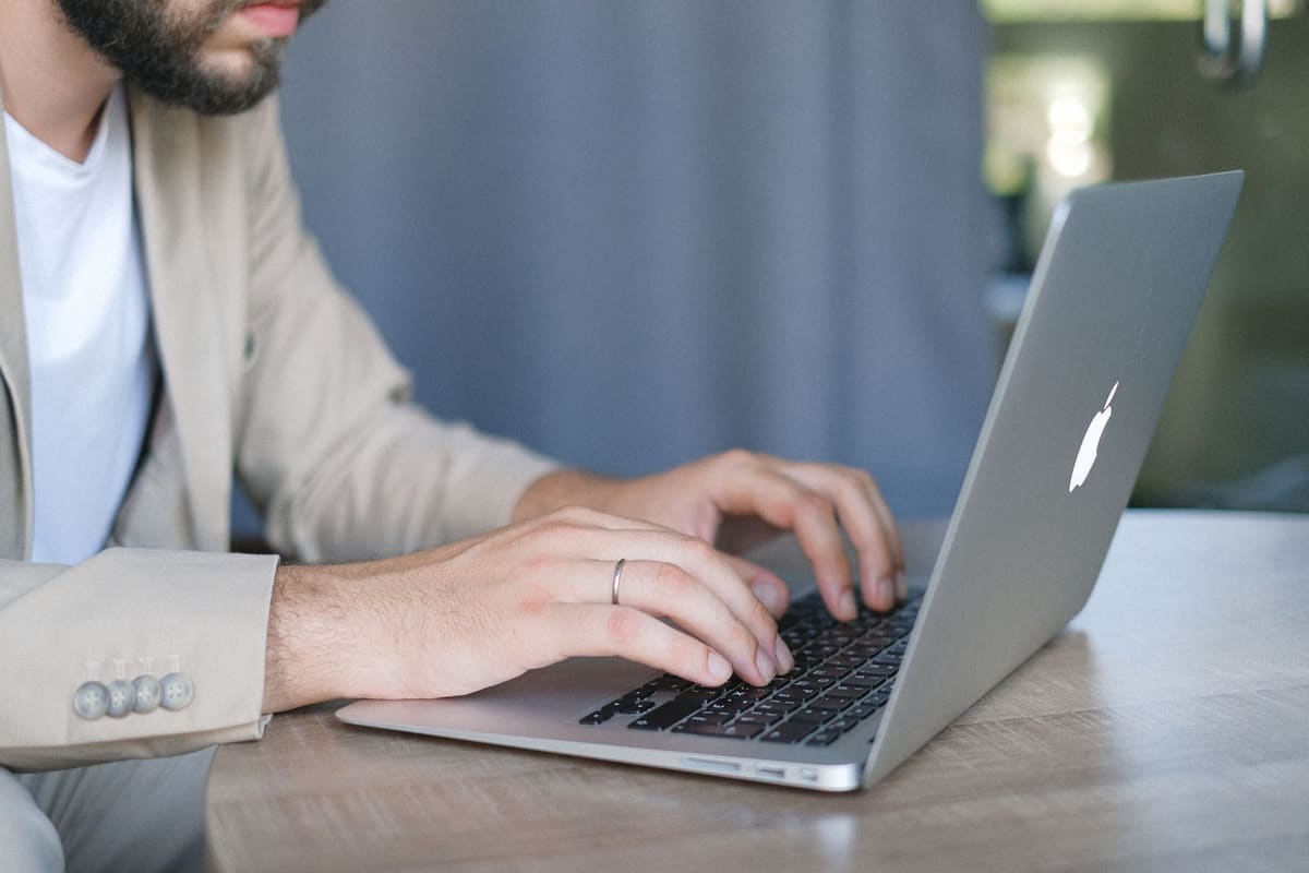 A person in a jacket typing on a laptop at a desk